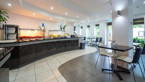 Een moderne keuken met een gebogen aanrecht, eettafels en stoelen.