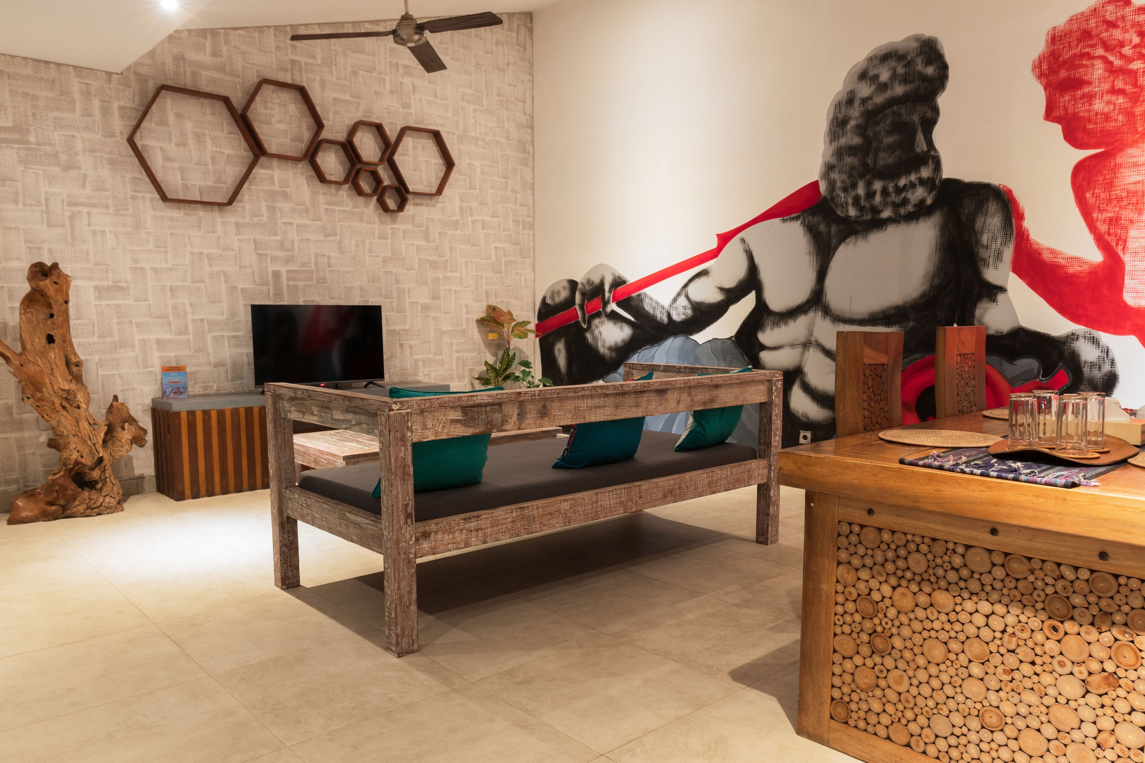 Un salon moderne avec un banc en bois, un téléviseur et une fresque murale.