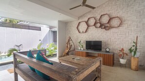 A modern living room with a wooden bench, a television, and decorative wall art.