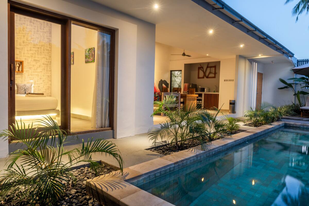A modern poolside area with a clear view of a bedroom, a dining area, and a living space.