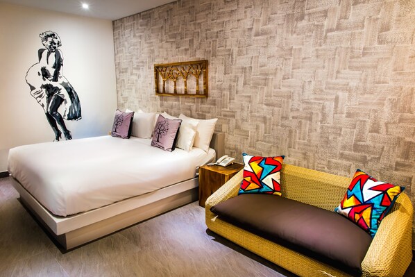 A bedroom with a bed, a sofa, a wall-mounted telephone, and a decorative wall piece.