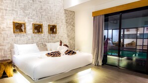 A modern hotel room with a large bed, a glass door leading to a pool area, and a brick-patterned wall.
