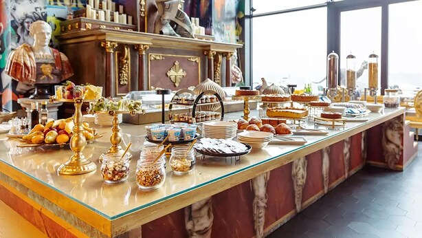 Een buffet met diverse gerechten en een standbeeld op de achtergrond.