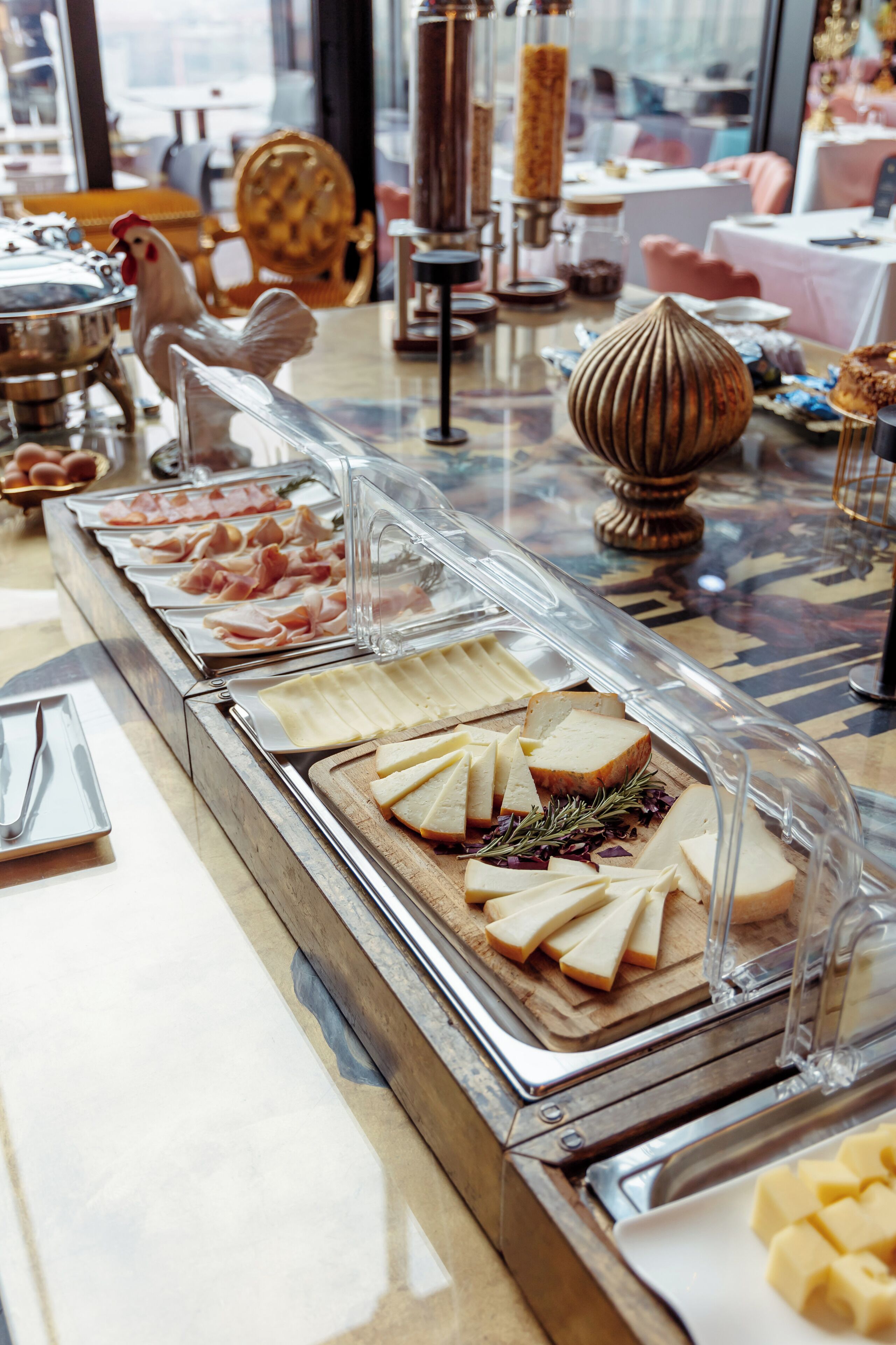 Buffet com diversas opções de comida, incluindo carnes, queijos e pão.