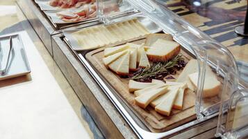 Buffet com diversas opções de comida, incluindo carnes, queijos e pão.