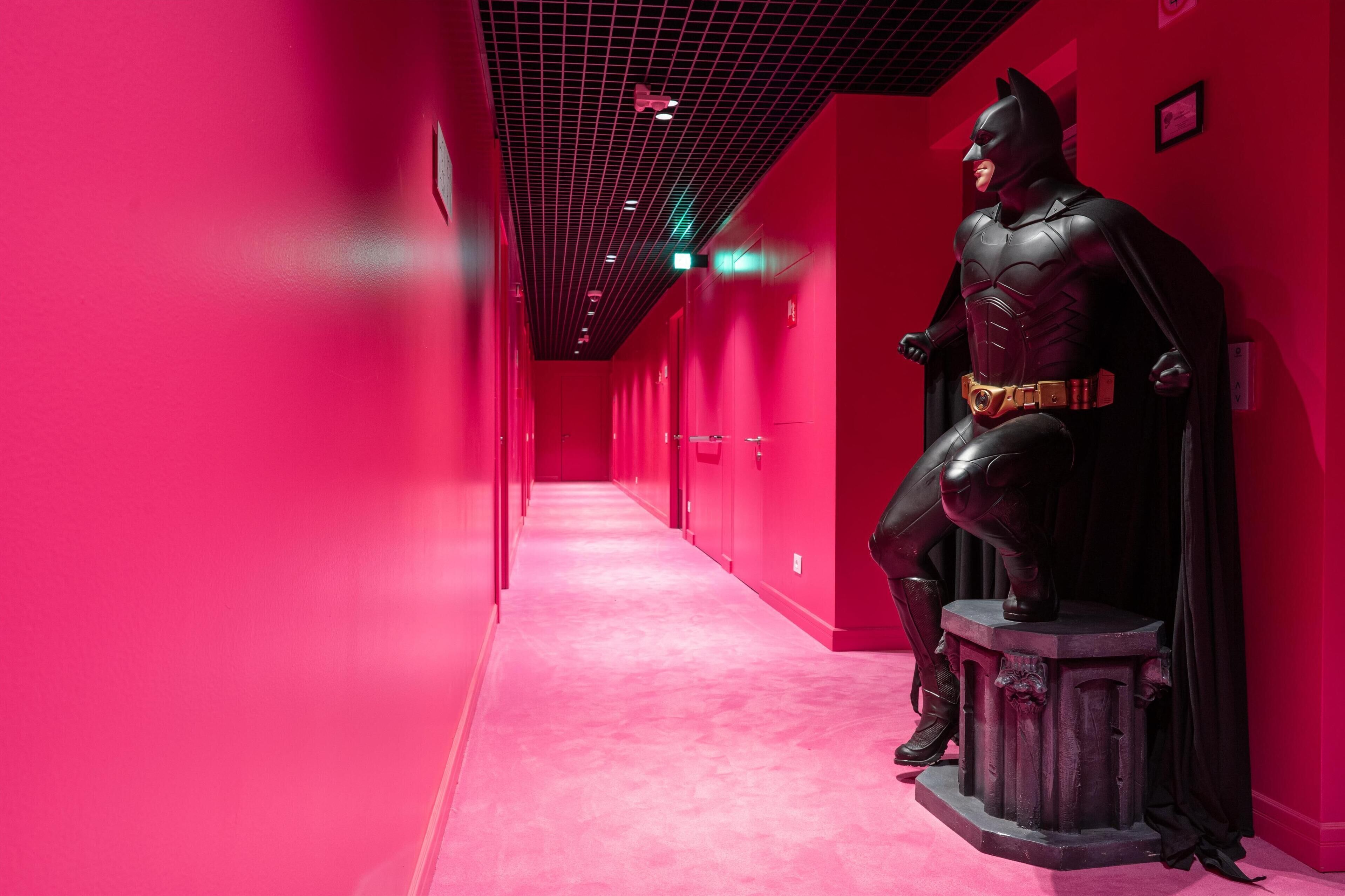 A statue of a superhero in a red-lit hallway.