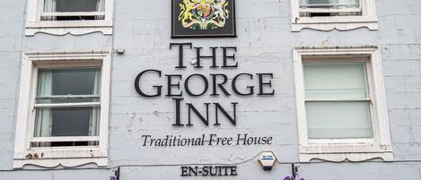 Un bâtiment portant une enseigne indiquant « The George Inn » et « Traditional Free House », ce qui signifie qu’il s’agit d’un établissement historique.