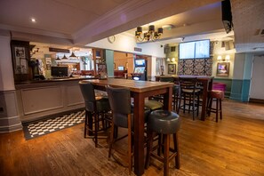 Un espace bar avec un comptoir en bois, des tabourets et un bureau dâaccueil.