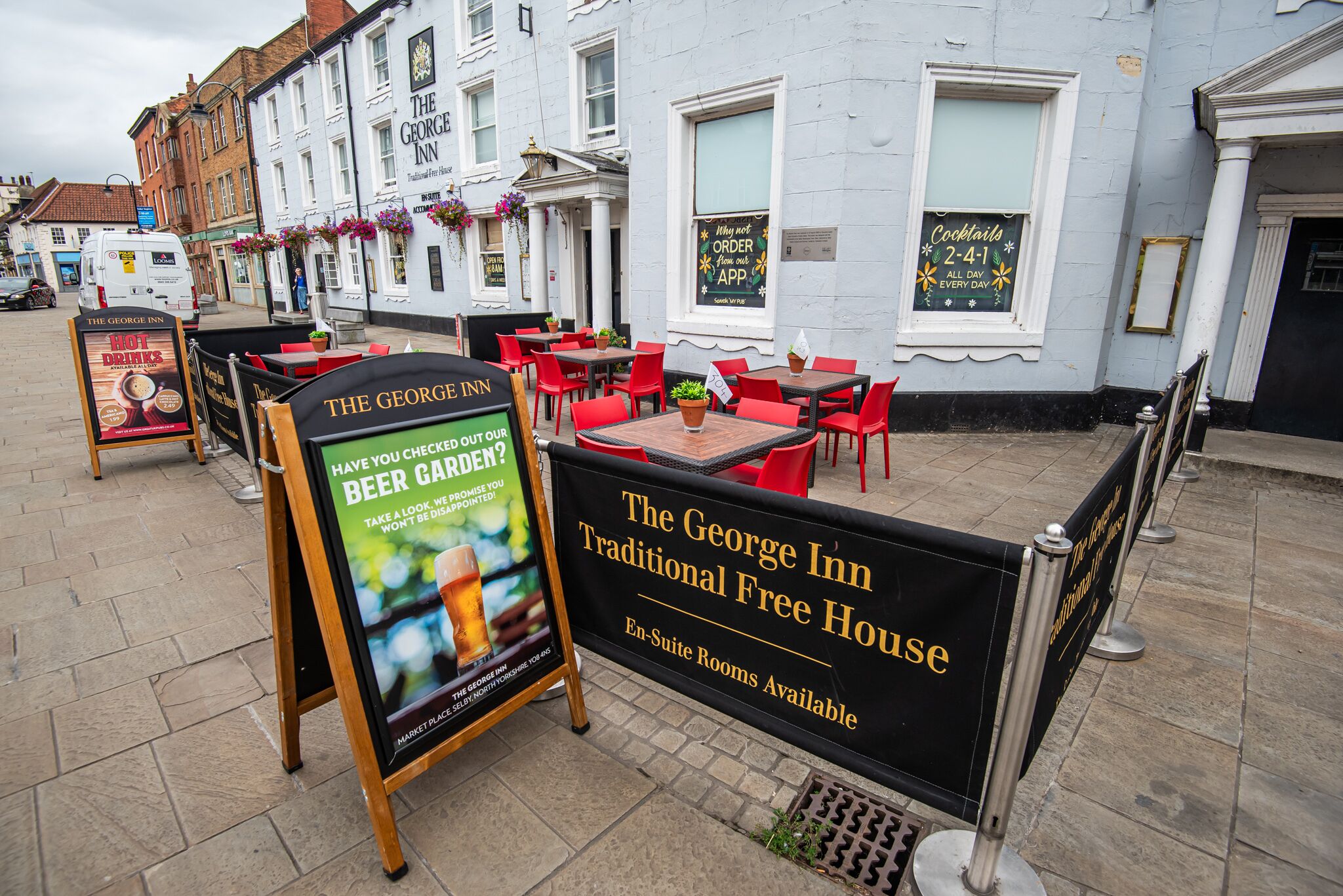 The George Inn with outdoor seating, a sign for traditional free house, and a signboard advertising beer garden.