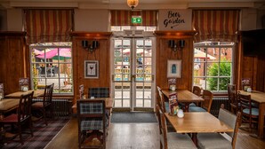 A restaurant interior with wooden paneling, a sign reading 'Beer Garden,' and a view of the outside through large windows.