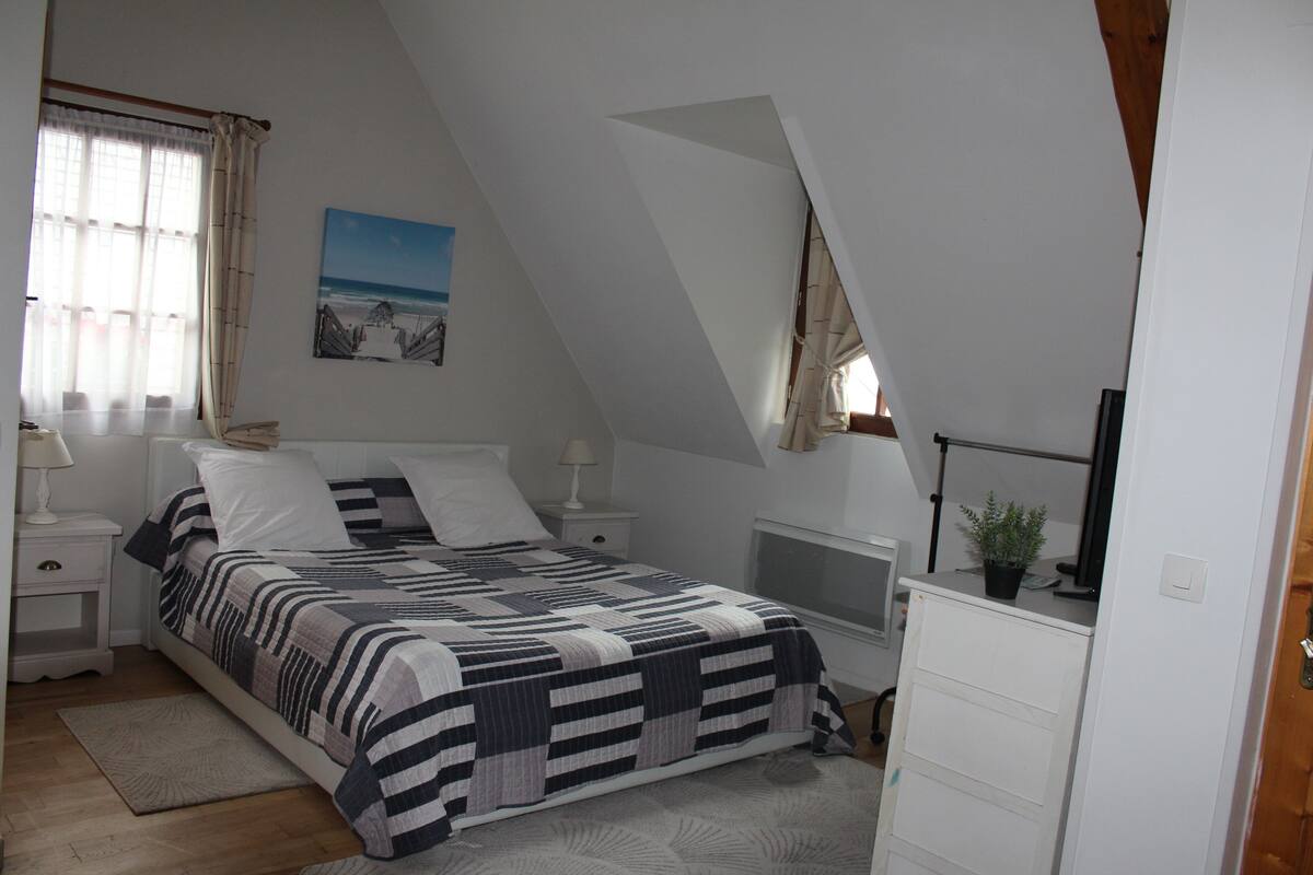 A bedroom with a bed, nightstands, a desk, and a dresser.
