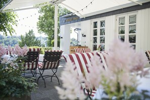 An outdoor seating area with striped chairs and tables, a sign reading "Parkhaus Hugel", and a view of trees and buildings in the background. - Parkhaus Hügel (Essen)