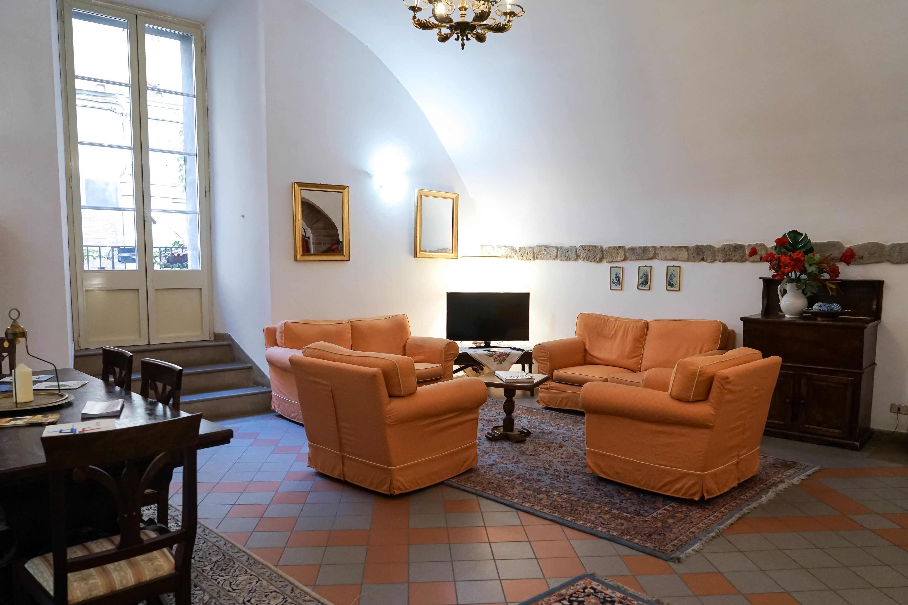 Un salon avec des canapés orange, un téléviseur et une cheminée.