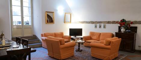 A living room with orange sofas, a TV, and a fireplace.