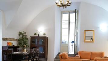 Ein geräumiges Wohnzimmer mit Essbereich, einer Chandelierleuchtre und einem großen Fenster.