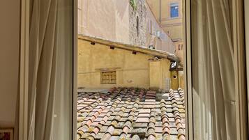 Ein Zimmer mit einem großen Fenster mit Blick auf ein Ziegeldach und ein Gebäude mit einer gelben Fassade.