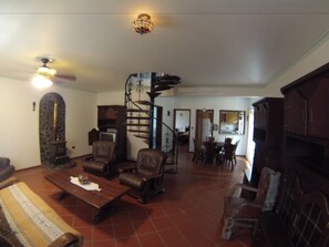 A spacious living room with a fireplace, a dining area, and a staircase leading to an upper level. - Vilar dos Carvalhinhos (Praia da Vitoria)