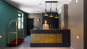 En receptionsdisk med en mörk skiva och guldfärgade detaljer, en klocka och en övervakningskamera ovanför.
