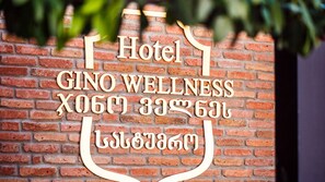A brick wall with a sign that reads "Hotel GINO WELLNESS" and some text in another language.