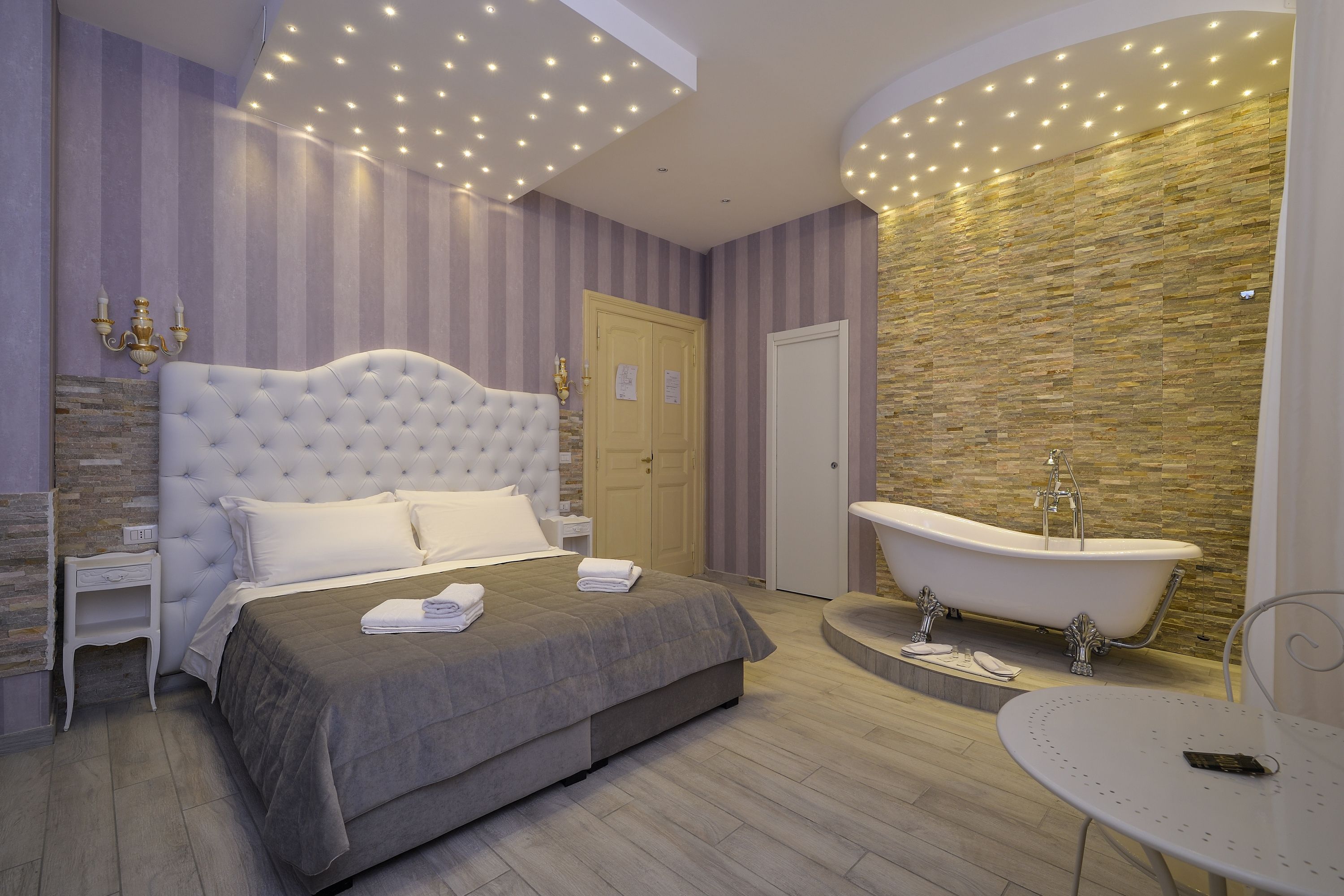 Un dormitorio moderno con una cama grande, una bañera y una mesita.