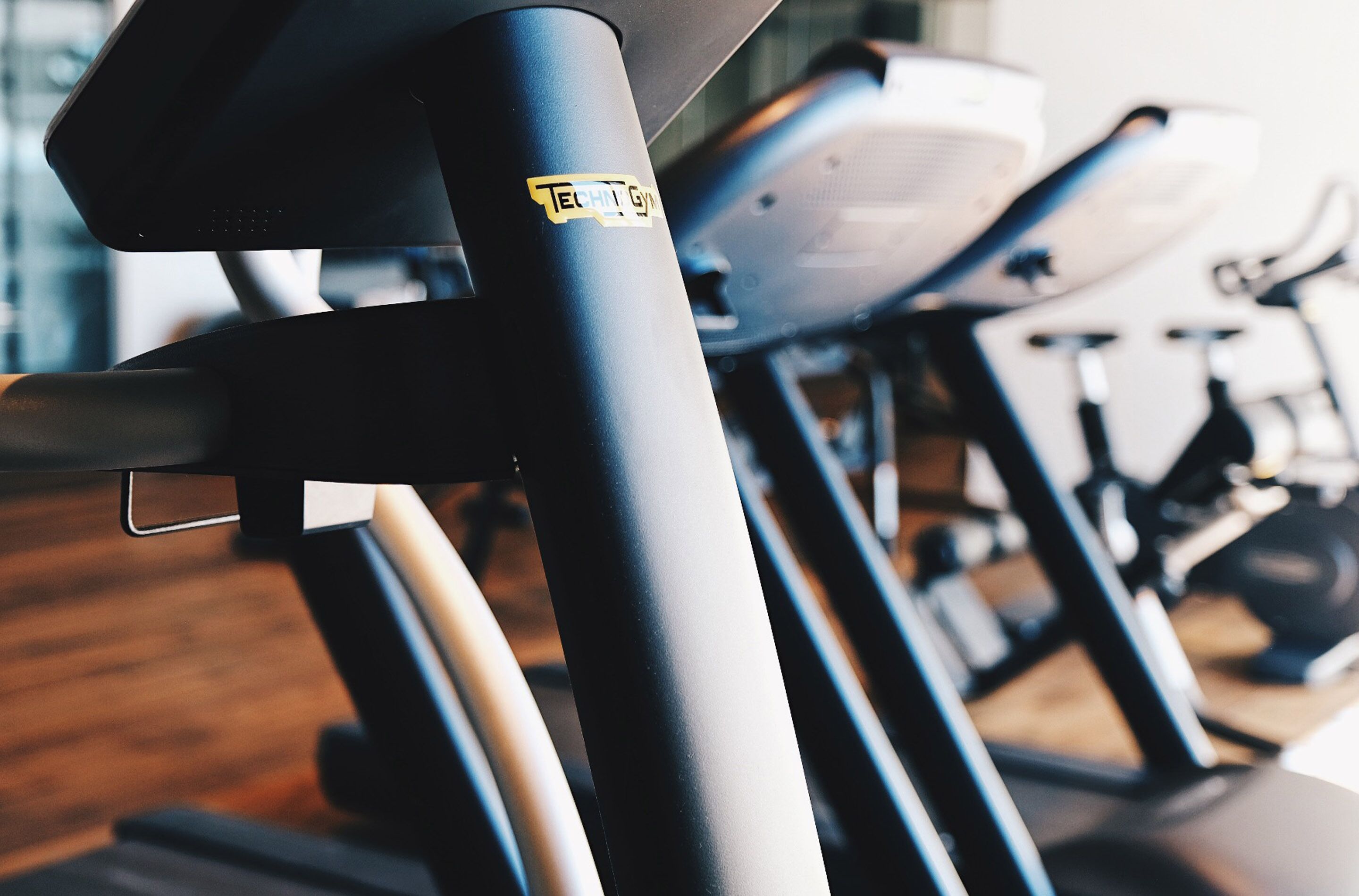 Una hilera de bicicletas estáticas en un gimnasio con piso de madera.