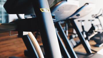 Una hilera de bicicletas estáticas en un gimnasio con piso de madera.