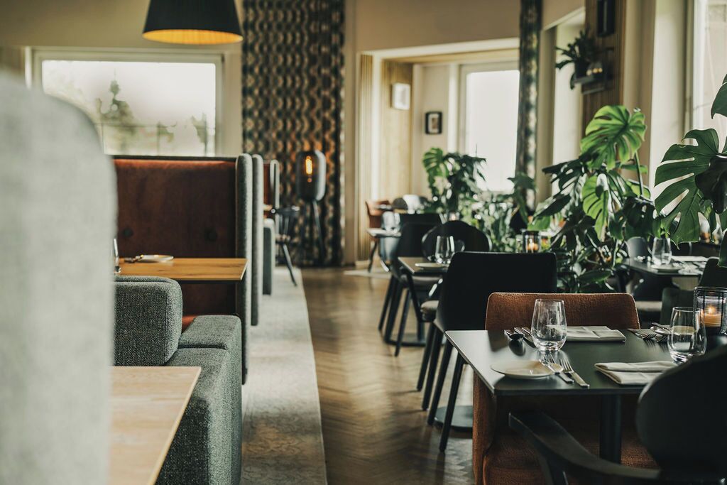Un ristorante con banconi e tavoli, pavimento in legno e piante in vaso.