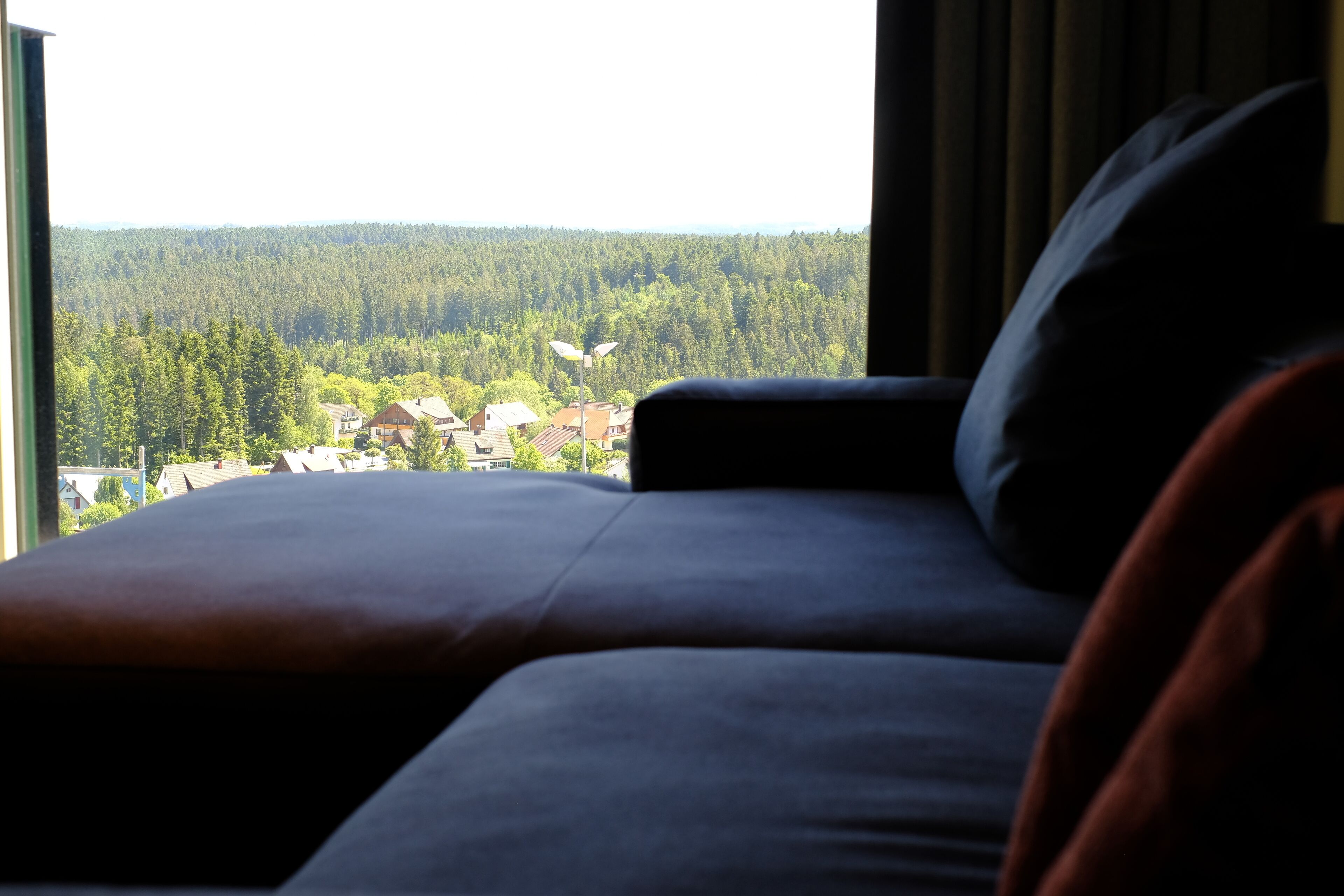 A bed with a view of a forest and houses.