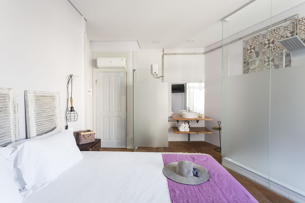 Un dormitorio moderno con cama, tocador con espejo y zona de ducha.