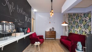 A cozy room with a blackboard wall, wooden floor, red velvet sofas, a wooden cabinet, and a wall clock. - The Bohemian Place (Aveiro)