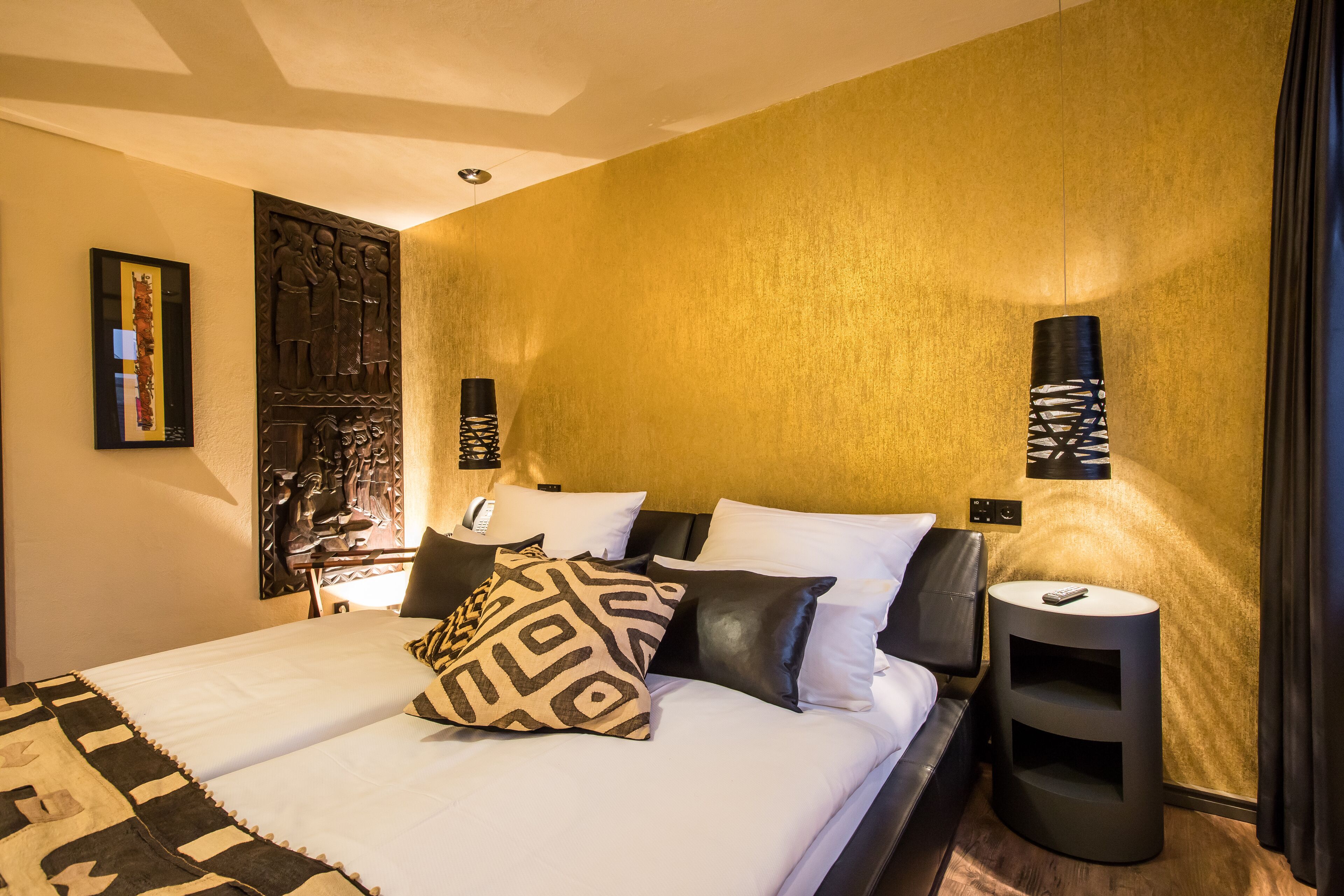 Una habitación de hotel moderna con una cama grande, una mesita de noche y una lámpara de pared.