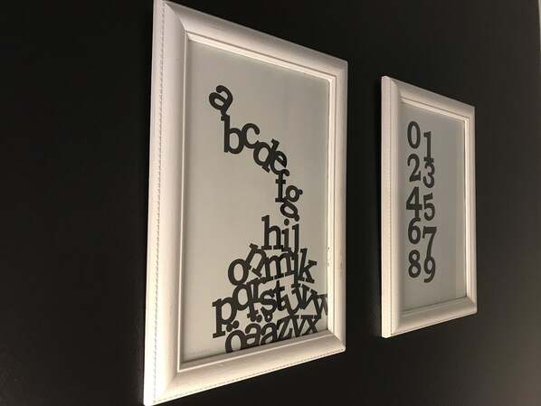 Two framed artworks on a wall, one with letters and the other with numbers.