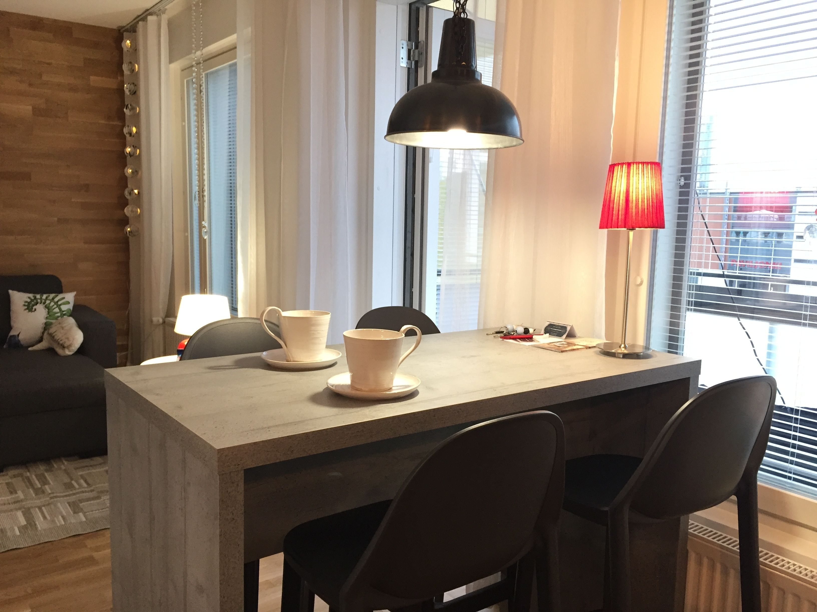 A modern dining area with a wooden table, two chairs, and a pendant light.