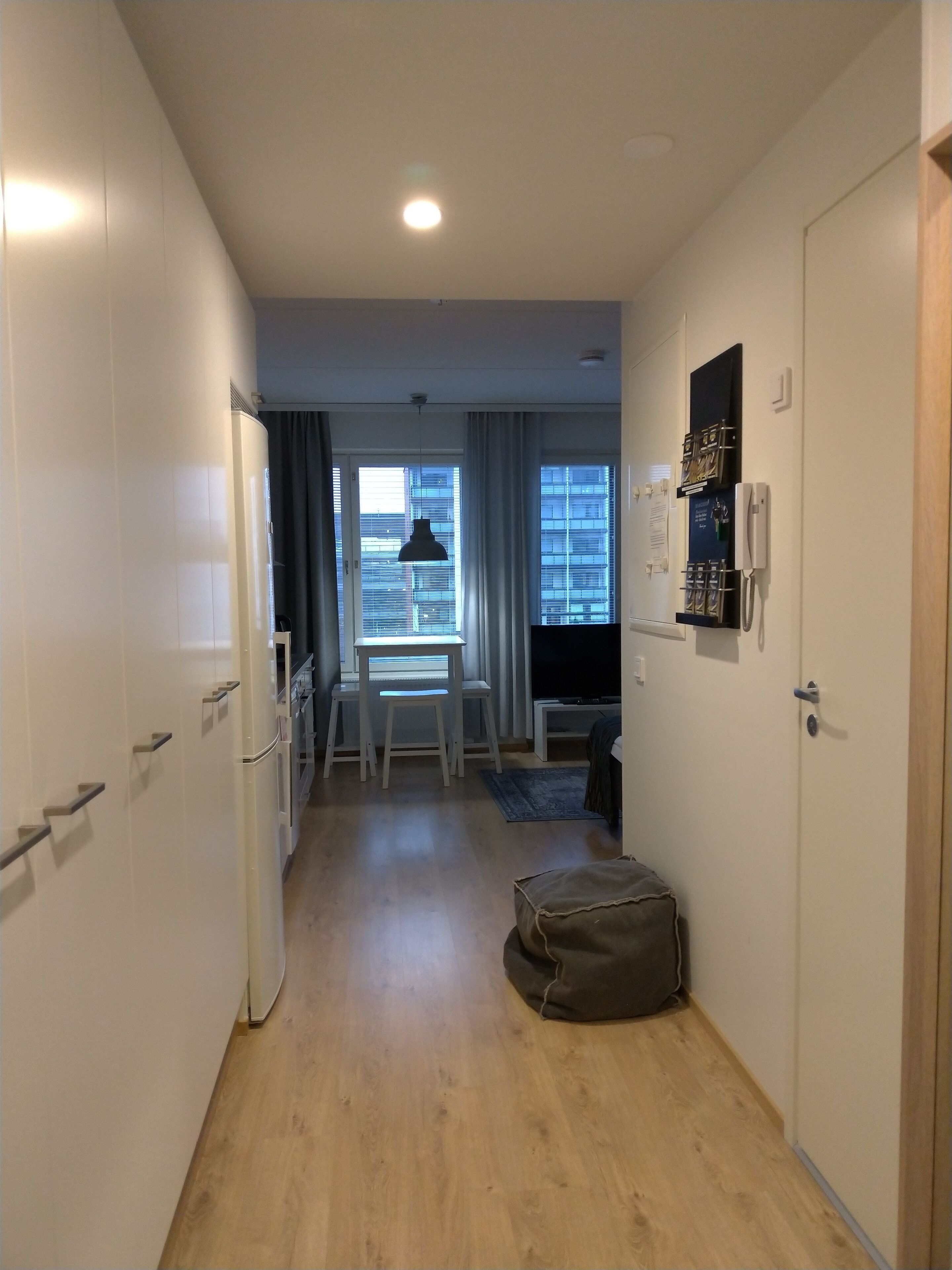A narrow hallway with a desk and chair, a small rug, and a bag on the floor.