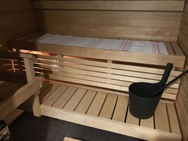 Una panca in legno nella sauna, con un asciugamano e un secchio nero.