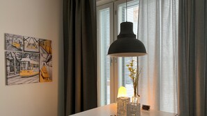 Un coin repas avec une table blanche, une suspension noire et un vase rempli de fleurs.