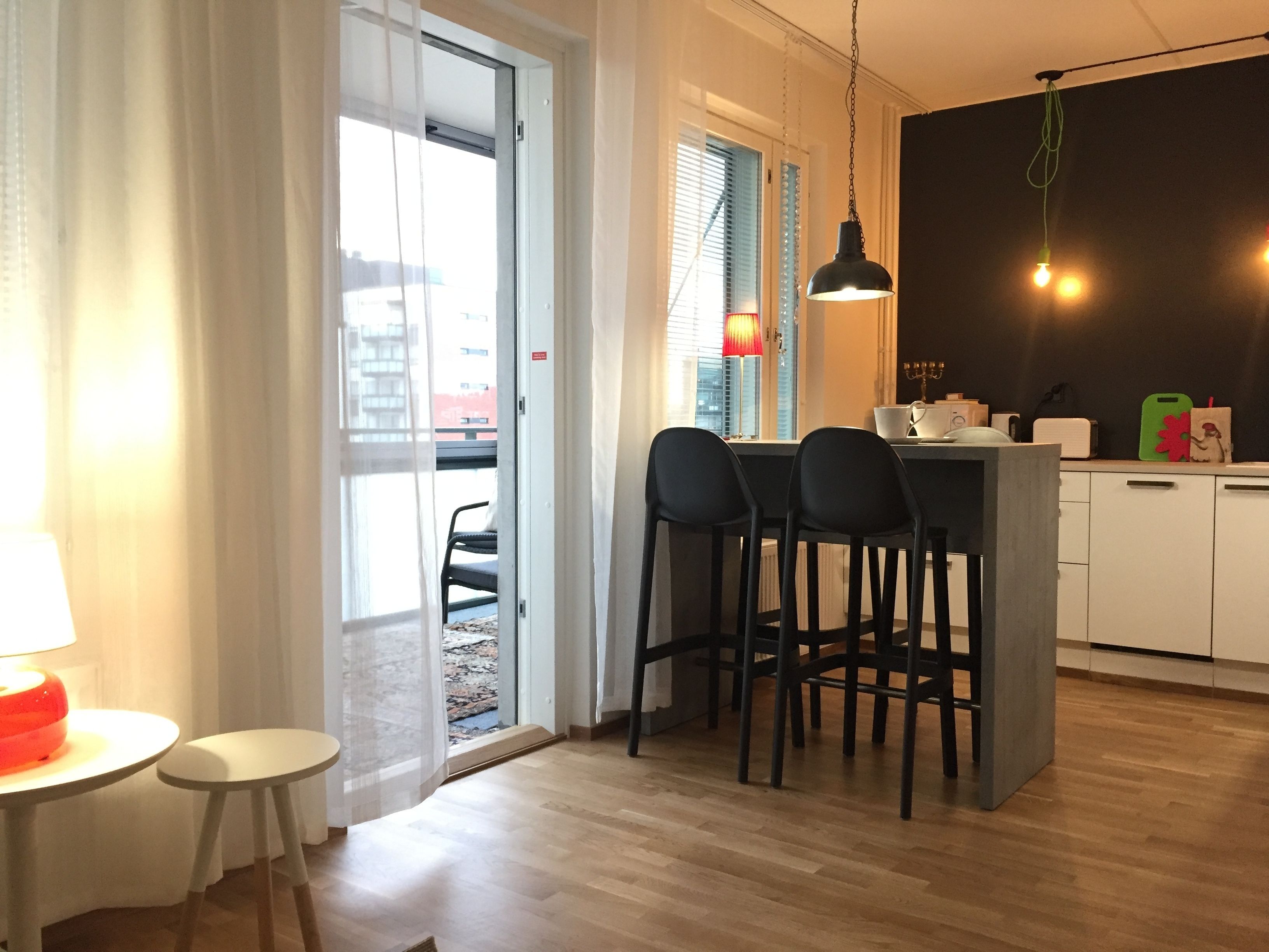 A modern kitchen with a central island, black bar stools, and a dining area with a table and chairs.