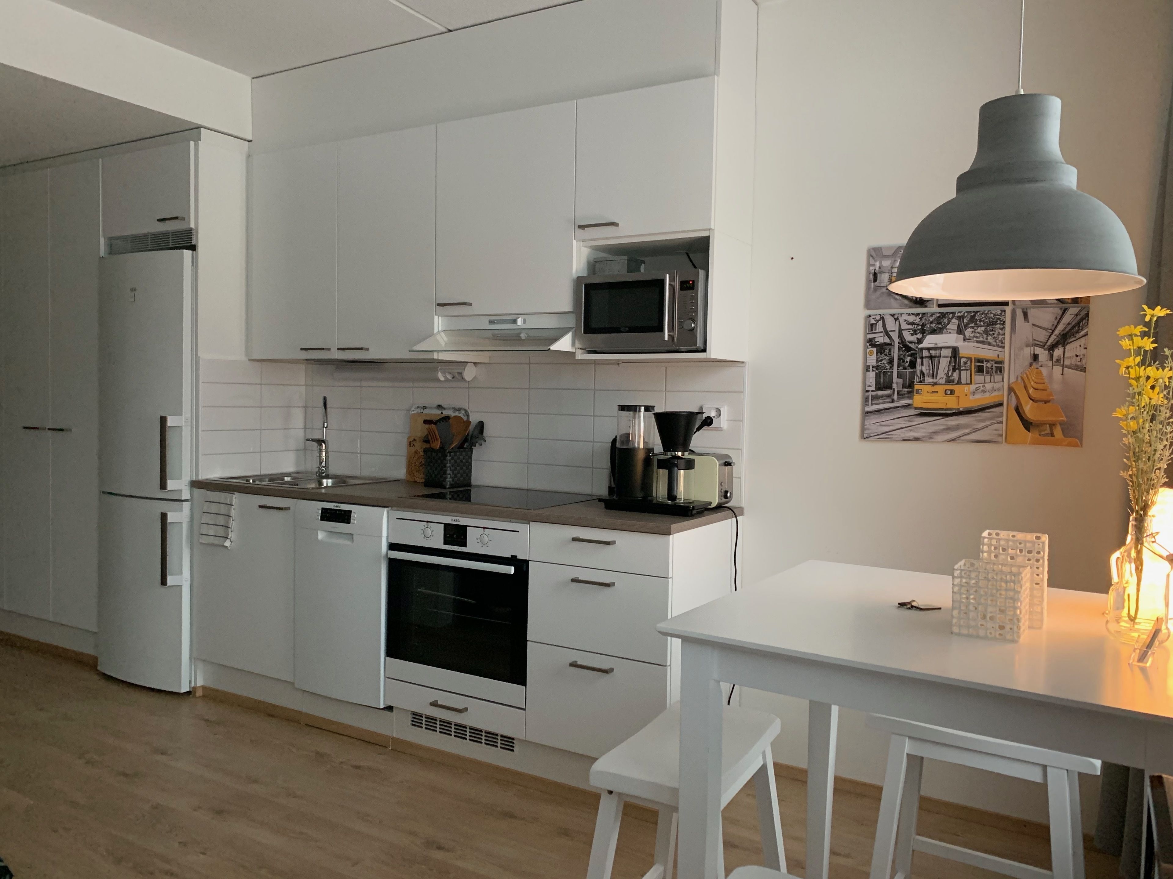 A modern kitchen with white cabinetry, a microwave, a coffee maker, and a dining area with a table and chairs.