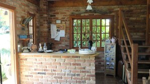 Cocina rústica con paredes de ladrillo, encimera de madera y ventana con vistas a la vegetación.