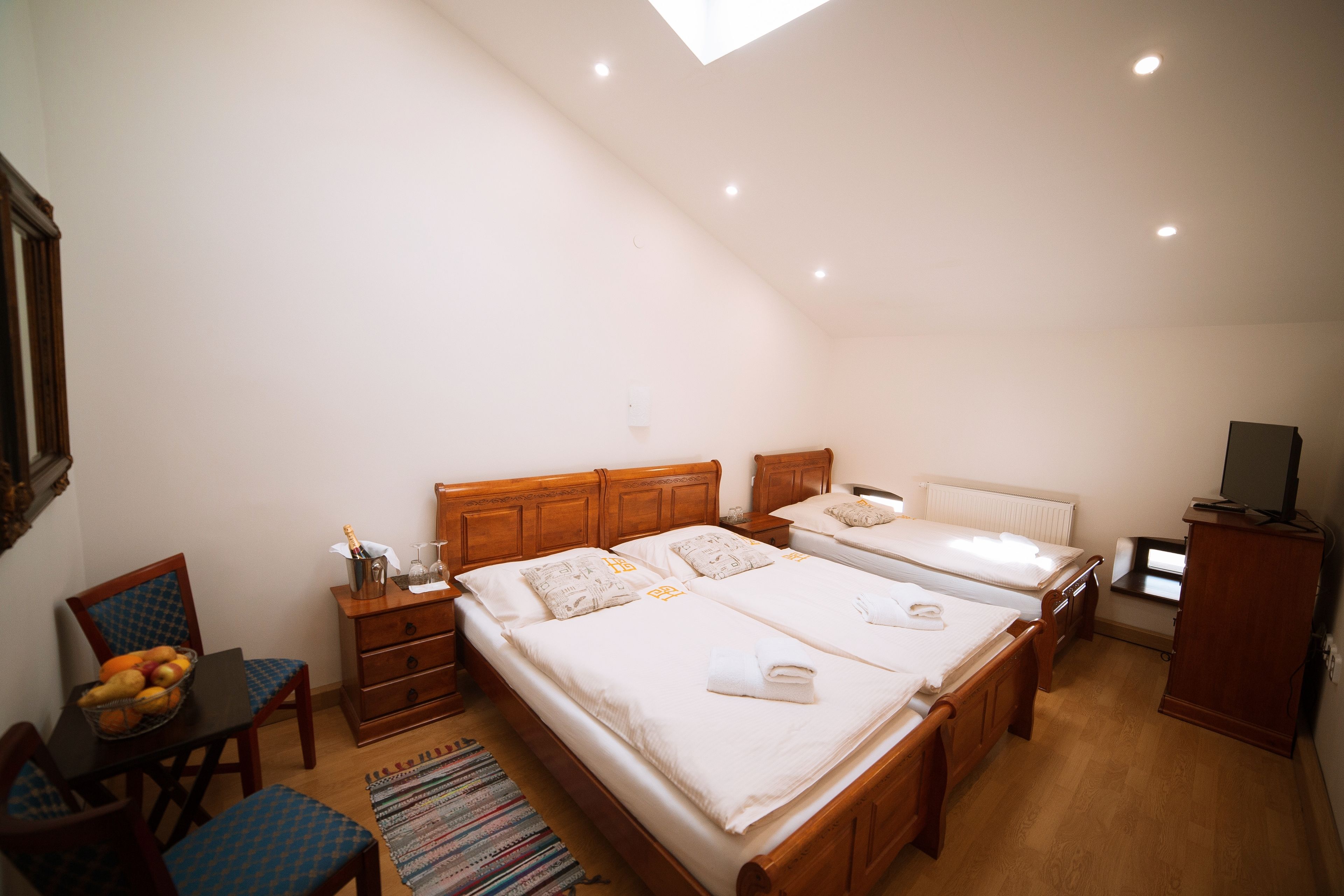 Un dormitorio con dos camas, un aparador de madera, un televisor y una zona de comedor con una silla y una mesa.