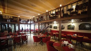Un restaurante espacioso con techos altos, barandillas ornamentales y un suelo con diseño.