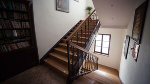 Una escalera con escalones de madera y barandillas negras, una estantería llena de libros y una planta en maceta.