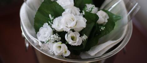 A bucket containing a bottle of champagne, glasses, and white flowers.