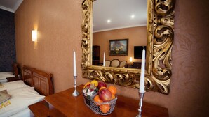 Habitación de hotel con cómoda de madera, cesta de frutas, dos velas y un espejo grande y ornamentado.