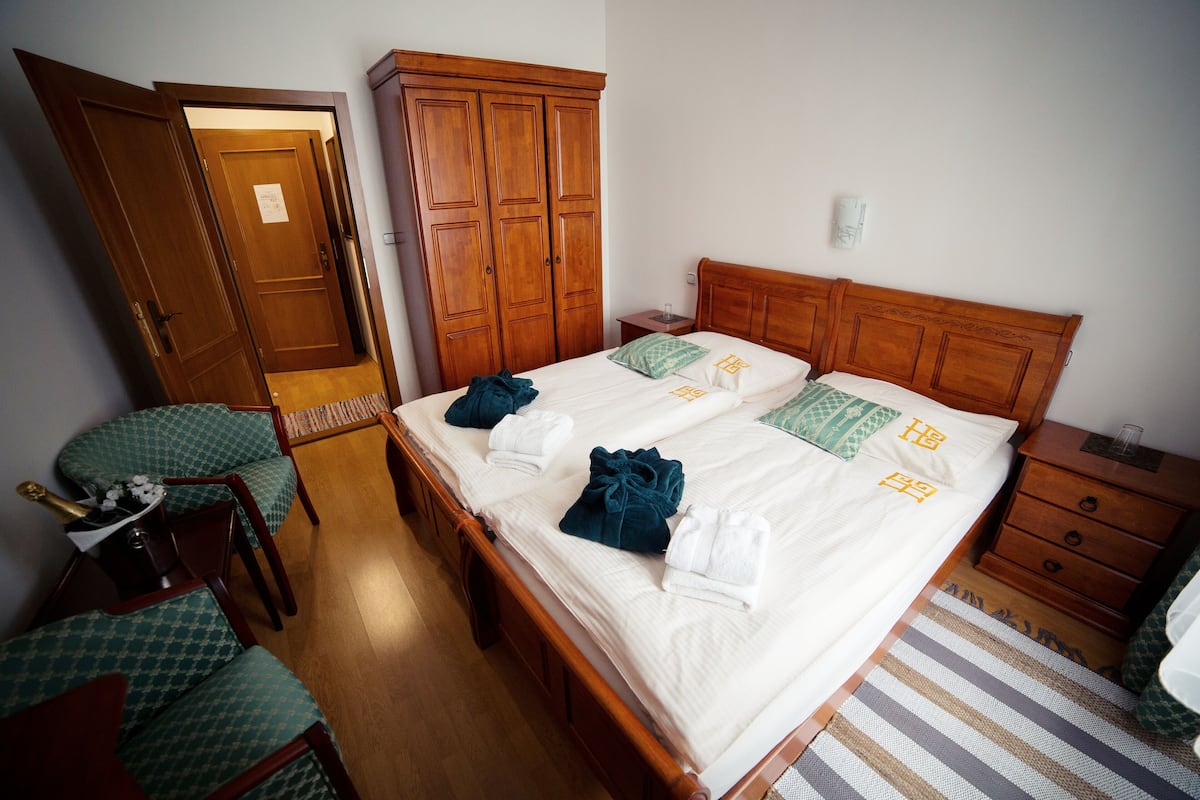 Una cama doble con cabecera de madera, dos mesitas de noche, un tocador, una silla y un armario.