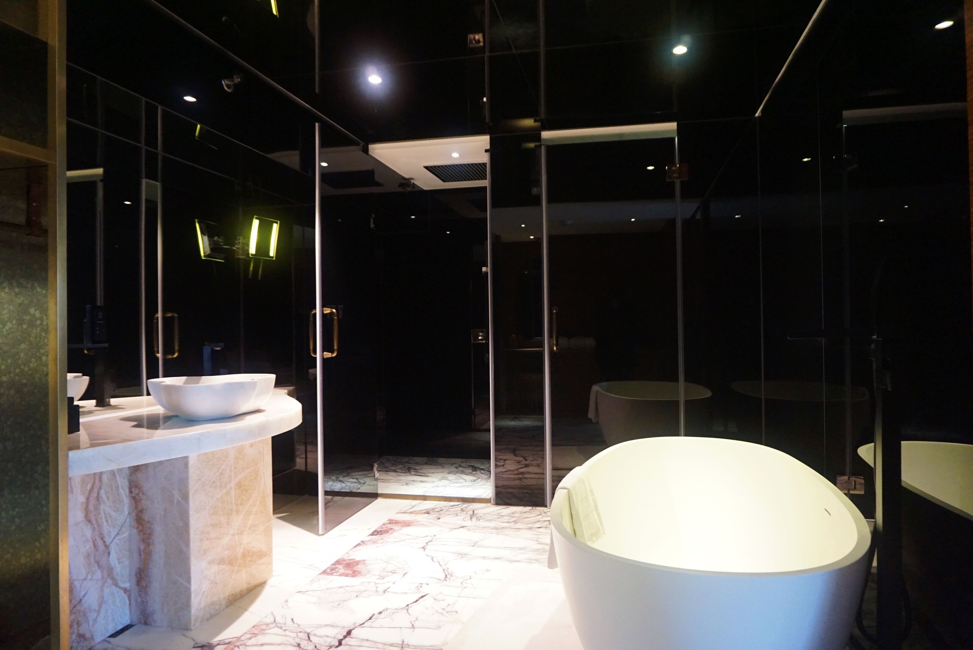 Un baño moderno con encimera de mármol, un lavamanos grande de color blanco y una bañera redonda.