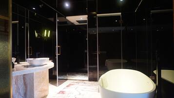 Un baño moderno con encimera de mármol, un lavamanos grande de color blanco y una bañera redonda.