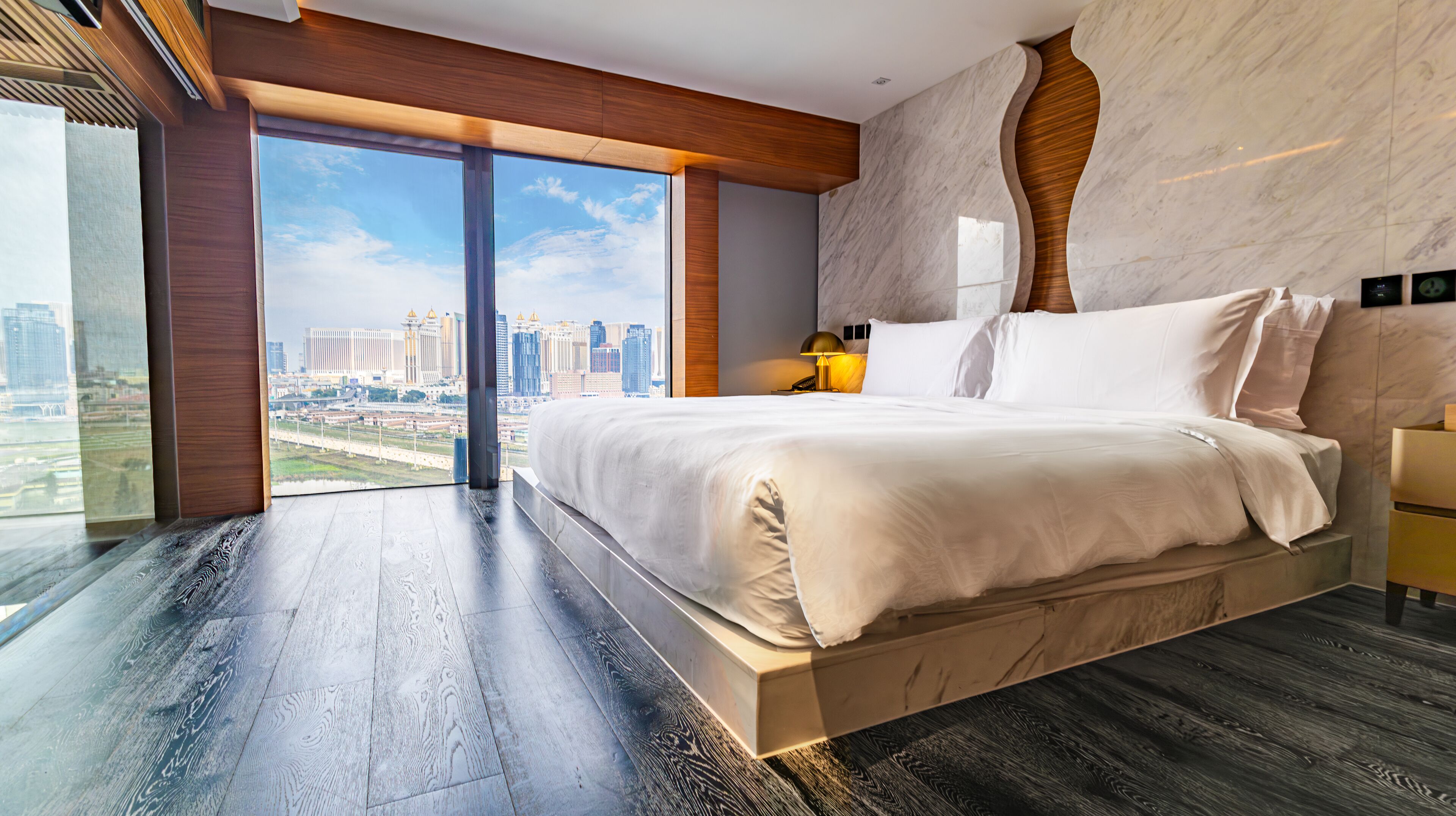 Een moderne slaapkamer met een groot bed, stadszicht en een houten vloer.