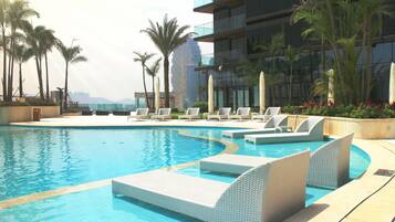 Una piscina al aire libre, sombrillas, tumbonas