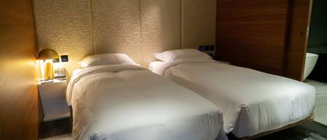 Une chambre d’hôtel avec deux lits simples, une table de chevet avec une lampe et une armoire en bois.